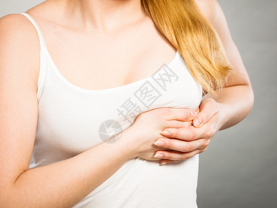 胸部疼痛健康问题的轻的生病的女人感种刺痛,抚摸着灰色的胸部患剧烈胸痛的女人背景