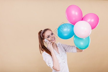 快乐的女孩玩彩色气球,同时手机上交谈节日,庆祝生活方式的工作室拍摄光明女孩边玩气球边打电话图片