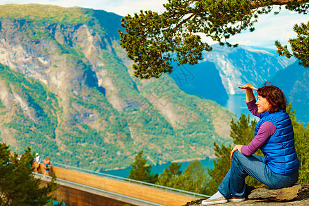 游客妇女越过Stestein瞭望台,看着挪威峡湾山脉的景色徒步旅行,旅途放松旅游景区路线极光游客享受山脉峡湾景图片