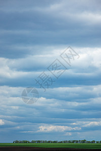 蓝灰色多云的天空以绿色条为天际线的雨背景文字的位置生态环境多云天空背景下的农田景观图片