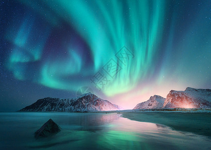 北极光海上,雪山城市灯光夜间挪威洛福滕岛的北极光极地灯光的星空冬季景观极光反射沙滩背景