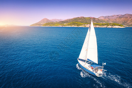 美丽的白色帆船蔚蓝的海洋明亮的阳光明媚的夏天晚上的鸟瞰克罗地亚的亚得里亚海景观游艇,山,透明的碧水,日落的天空图片