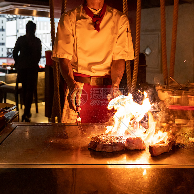 烤牛肉铁板烧食谱日本烤牛肉战斧牛排烹饪锅用刮刀与火焰背景图片