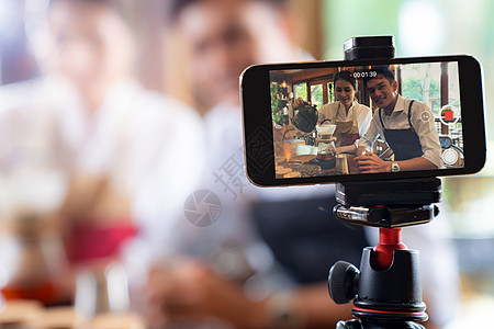 轻的亚洲业主企业家Vlog回顾咖啡馆咖啡店,并生活社交媒体上,咖啡馆用智能手机进行线营销用于启动小企业营销消费主义图片