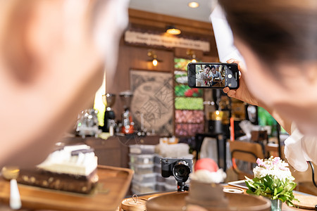 两位轻的亚洲业主企业家博主的后视镜,回顾咖啡馆咖啡店的社交媒体线营销咖啡馆用于启动小企业营销消费主义图片