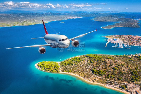 飞机在夏季日落时飞越小岛屿和海面上空图片