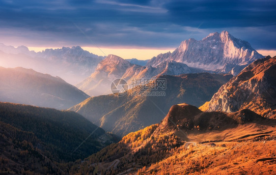 秋天落日时美丽的山峰秋天时日落的多洛米山意大利风景与岩石日光束森林山丘橙色草和树木多彩的天空风景与秋天的雾中山谷风景图片