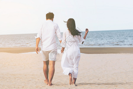 海边漫步夫妻或情侣海边沙滩上散步背景