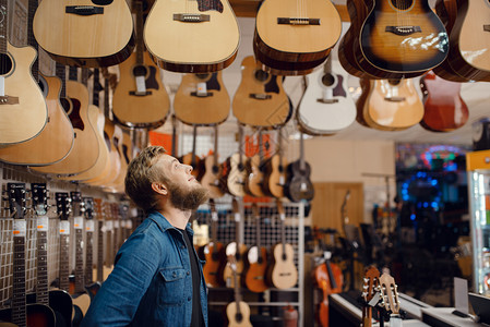 音乐店选择吉他的男音乐家男性的高清图片素材
