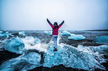 女探险家在阿拉斯加冰岛沙滩高兴挥手图片