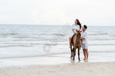 年轻夫妇在热带海滩骑马背景图片