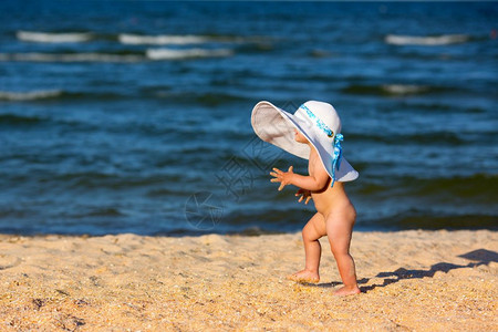 穿着大帽子的小女孩在海滩上散步图片