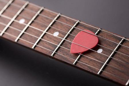 电吉他弦中的红色拨片特写图片
