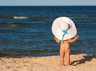 戴着大帽子的小女孩站在海滩上看海图片