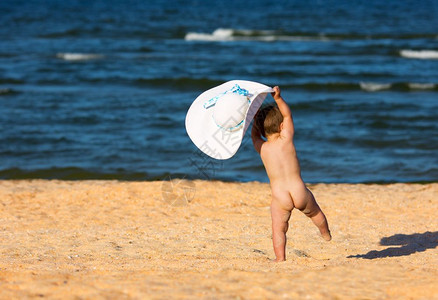 沙滩上的风吹着戴大帽子的小女孩图片