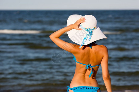 戴着大帽子的性感女孩在沙滩上看海图片
