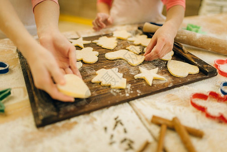 两个小女厨师在厨房木板上撒面粉做饼干图片