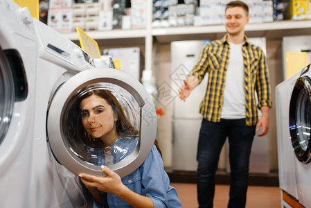 家用洗衣机年轻夫妻在电子商店购买家用电器背景