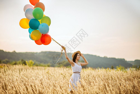 漂亮女孩在麦田里手拉气球图片