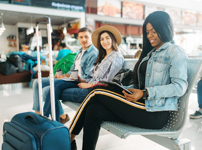 3名旅客携带行李坐在机场等候厅图片