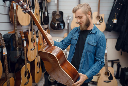 音乐店的吉他选手音乐器店的组合男音乐家购买设备支架高清图片素材