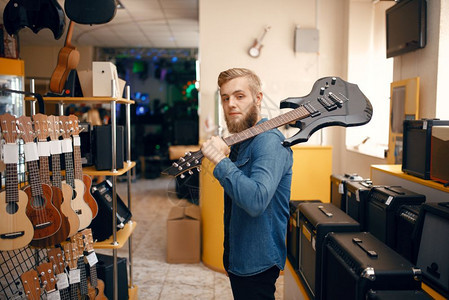 男青年音乐家在音乐器店选购买乐器顾客高清图片素材