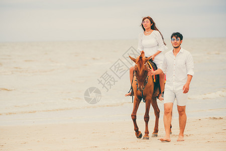 夫妇在热带海滩骑马背景图片