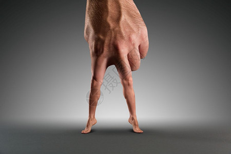 男手用腿而不是手指在灰色之上男手用腿图片