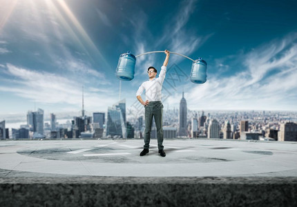 自信的商人举起俩桶水以城市为背景的商业概念图片