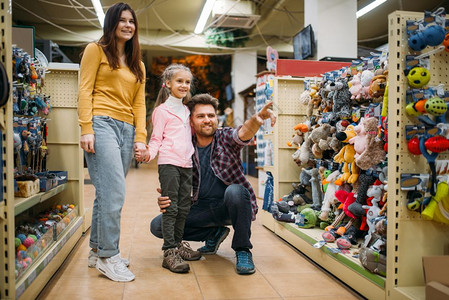 家庭游父母亲和女儿在宠物店选择玩具背景