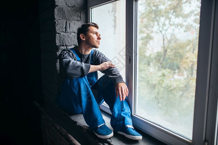 坐在黑暗房间窗边的低压男子精神病患者人有压力的抑郁症图片