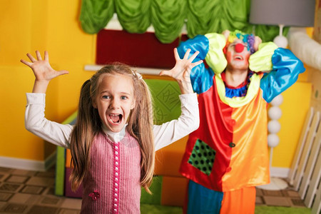 小女孩在生日派对上和不高兴的小丑玩耍图片