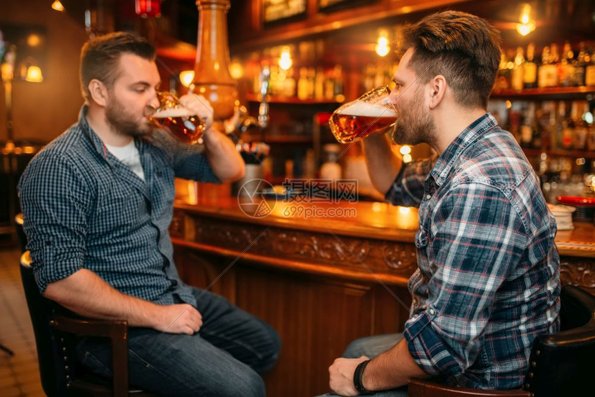 两个笑着的男朋友在酒吧的柜台喝啤图片