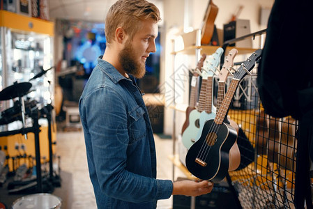 在音乐店中选择ukle吉他音乐器店中的各种组合男音乐家购买设备图片