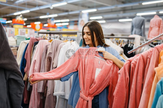 年轻女性在服装店挑选浴袍图片