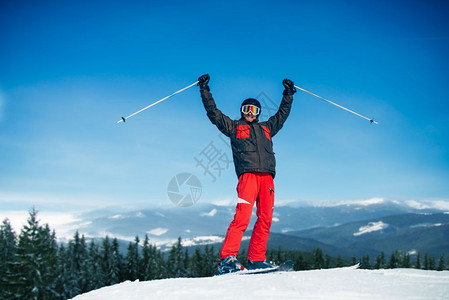 山顶男滑雪运动员喜悦的举起手图片
