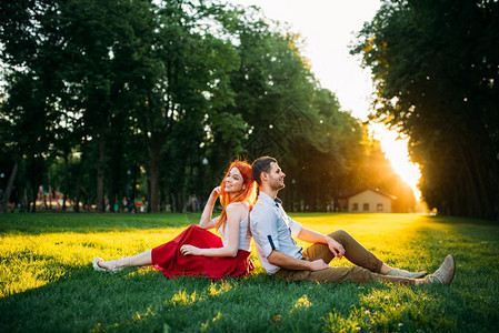 情侣坐在夏日公园的草地上图片