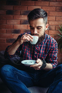 帅哥坐着拿着杯子图片