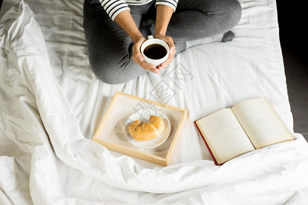 妇女早上在床看书或报纸喝咖啡图片