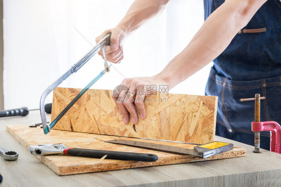 木匠仔细研究工的程计划他是在工作场所成功的创业者在与切割工一起的建筑地作上打钉子图片