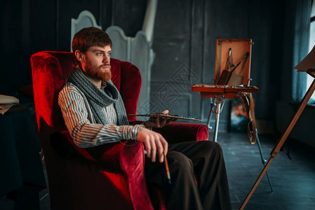 艺术表演画家手持调色盘和刷子的坐在椅上背景