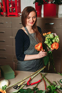 女花匠一边做装饰花束一边用花工作图片
