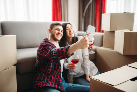 年轻夫妇用纸板盒做自拍搬到新房子公寓庆祝夫妇用自拍对箱子搬家图片