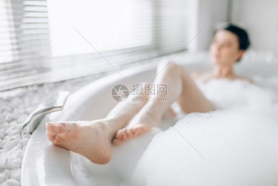 在洗澡的年轻女子躺在洗澡的泡沫模糊视觉放松在豪华浴室图片