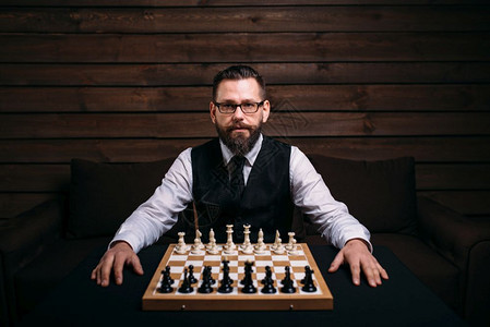 戴眼镜的男玩家坐在棋牌板上与盘的片段对齐策略游戏概念图片