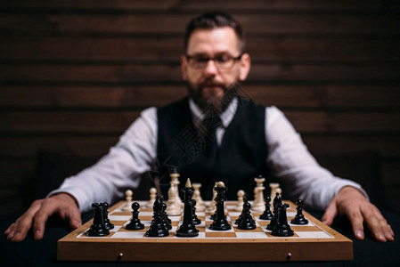 男玩家在眼镜中的男玩家坐在棋板上与类组策略游戏概念男玩家在棋类板上与组图片