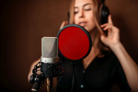 在音乐室录制一首歌的女歌手背景图片