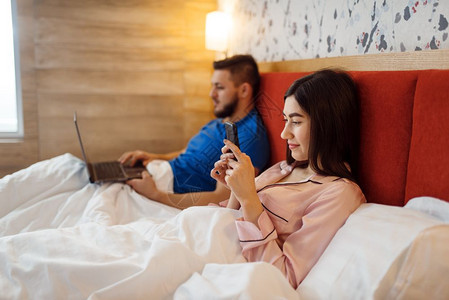 情侣在床上玩电子设备图片