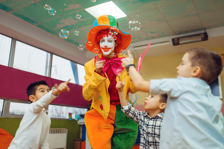 孩子们与小丑一起快乐的玩耍吹泡泡图片