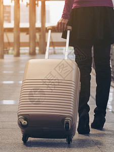 携带旅行袋或李在机场终点站行走前往国外旅的妇女者图片